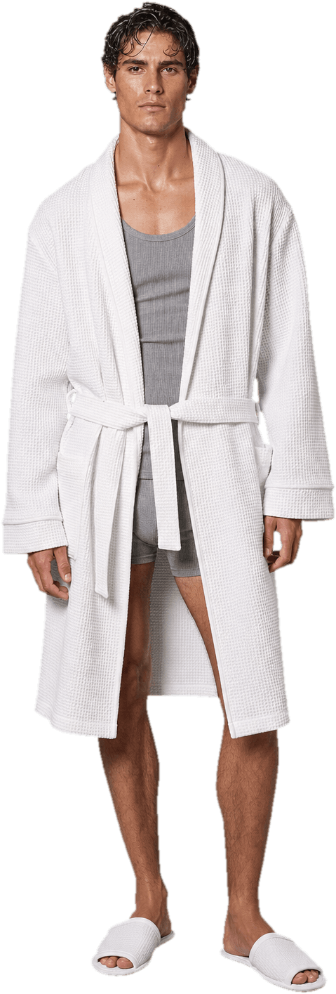 A thick oversized white waffle-cotton robe belted at the waist over a grey ribbed tank and shorts, with flat white slippers