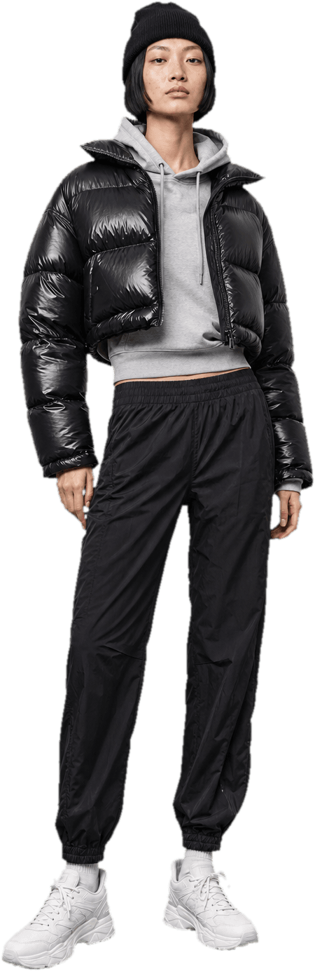 A glossy black cropped puffer jacket over a grey hoodie, with black nylon track trousers, a black beanie and white chunky sneakers
